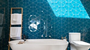Un bagno moderno con una vasca freestanding, un water e un porta asciugamani con asciugamani.