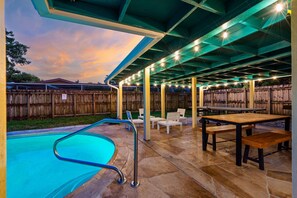 Eine Terrassengaststätte mit Pool, Sitzgelegenheiten und Tischen.