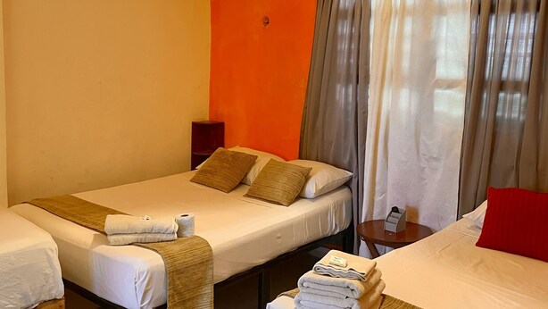 Une chambre d’hôtel avec deux lits, une petite table et une fenêtre avec des rideaux.
