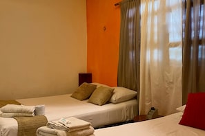 Ein Hotelzimmer mit zwei Betten, einem kleinen Tisch und einem Nachttisch.