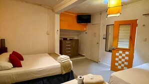 Une chambre d’hôtel avec deux lits, une télévision, un miroir et une porte à motifs à carreaux.