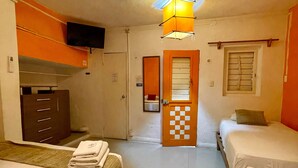 Une chambre d’hôtel avec deux lits, une armoire, une télévision et une porte à carreaux.