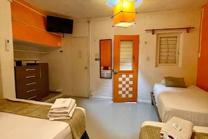 Ein Hotelzimmer mit zwei Betten, einem Kleiderschrank, einem Fernseher und einer karierten Tür.