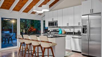 A modern kitchen with white cabinets, stainless steel appliances, and a central island with bar stools.