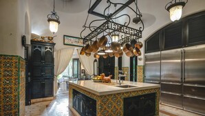 A kitchen with a central island, stainless steel appliances, and decorative copper pots hanging from the ceiling. - Hacienda Palancar Sian Ka an Luxe 11br (Tulum)