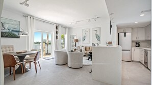 A modern kitchen with white cabinets, a central island, and a dining area with a round table and chairs. - Walk to Ft Lauderdale Beach - Water Views Pool (Fort Lauderdale)