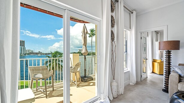 A balcony with a view of the sea and cityscape, a wicker chair, a small table, and a lamp. - Walk to Ft Lauderdale Beach - Water Views Pool (Fort Lauderdale)