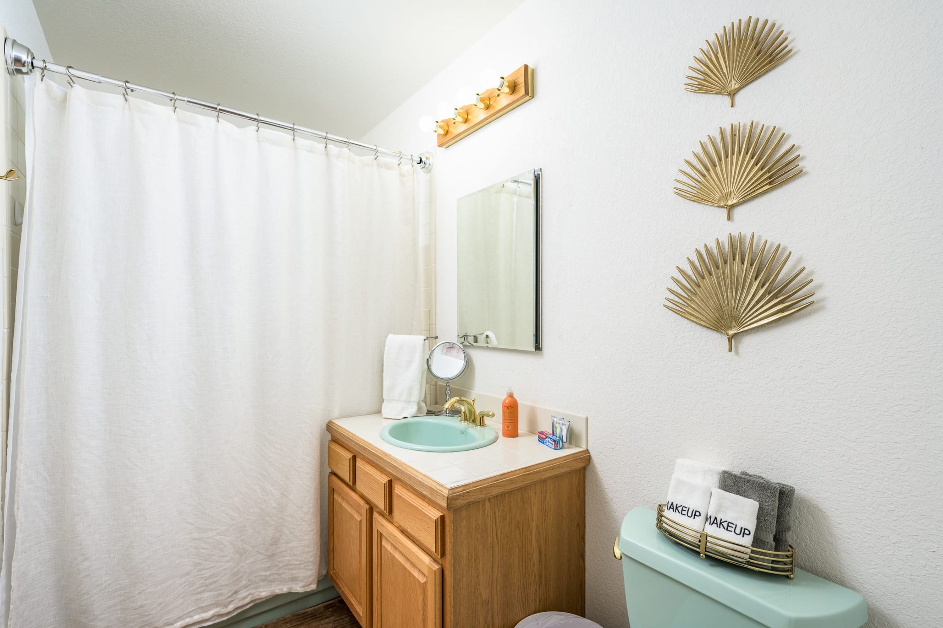 Un baño con cortina de ducha, un lavamanos con espejo y decoración en las paredes.