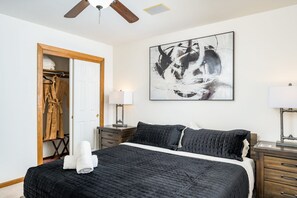 A bedroom with a bed, bedside tables, a wardrobe, and a ceiling fan.