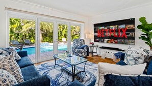 A modern living room with a large TV, a pool view, and a cozy seating area. - Cypress Cove - HTD Pool Near Lauderdale By The Sea (Fort Lauderdale)