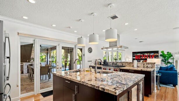 A modern kitchen with a large island, pendant lighting, and a view to an outdoor patio. - Cypress Cove - HTD Pool Near Lauderdale By The Sea (Fort Lauderdale)