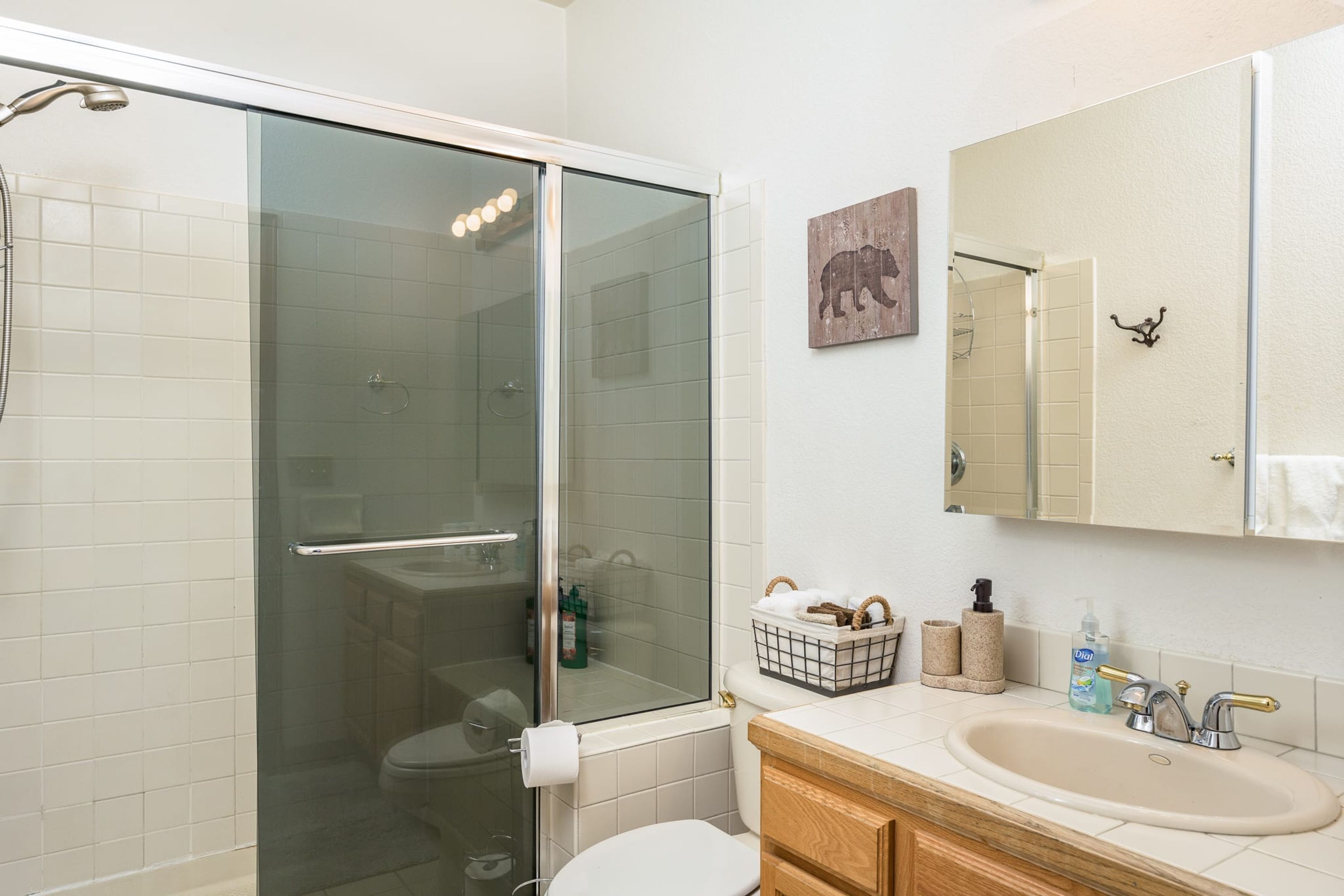 Une salle de bain avec une douche à parois de verre, des toilettes, un lavabo avec un miroir et un porte-serviettes.