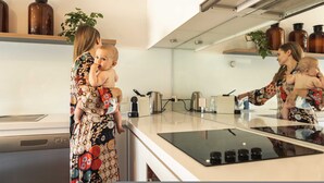 Une cuisine moderne dotée d’un îlot central, d’appareils électroménagers en acier inoxydable et d’un revêtement mural réfléchissant.