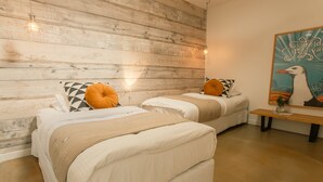 Une chambre avec deux lits, un lambris en bois, un banc et un luminaire fixé au mur.