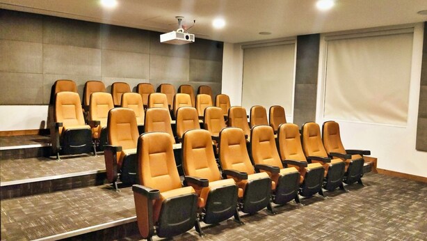 Une salle de conférence avec des rangées de chaises, un projecteur et un grand écran.