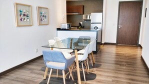 Une cuisine moderne équipée d’un réfrigérateur, d’un four à micro-ondes et d’une cuisinière. On y trouve également un coin repas avec une table et des chaises en verre.