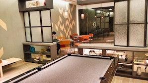 Une table de billard dans un décor intérieur moderne, avec des coins salon et des étagères décoratives.