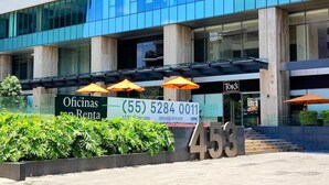 A modern building with a sign for 'Oficinas en Venta' and a contact number. There are outdoor umbrellas and a number '453' displayed prominently. - Luxurious High-rise HS Wifi Amazing City Views (Mexico City)