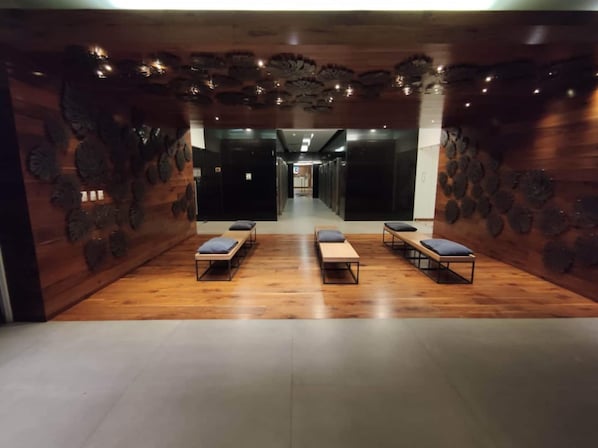 A spa room with wooden walls, a central bench area, and a hallway leading to other rooms.