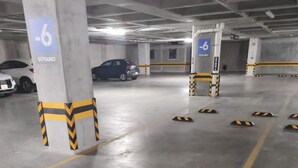 Un estacionamiento subterráneo con pilares de concreto marcados con números y señales direccionales.
