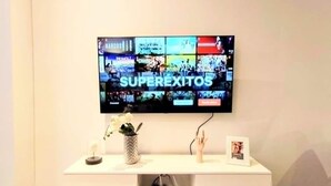 Un televisor de pantalla plana montado en una pared que muestra la palabra "SUPEREXITOS".