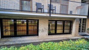 Ein zweistöckiges Gebäude mit einem Balkon, großen Fenstern mit schwarzen Querstreben und einem Garten im Vordergrund.