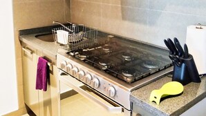 A kitchen with a stove, oven, and wooden cabinets. - Stunning Hi-rise Pool-jacuzzi gym HS Wi-fi (Mexico City)