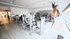 A gym with various exercise equipment, a wooden floor, and a large window on the right. - Stunning Hi-rise Pool-jacuzzi gym HS Wi-fi (Mexico City)