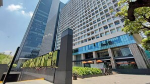 A modern building with a glass facade, a large entrance with a sign, and a surrounding landscaped area. - Alluring Views Luxuriously Appointed in Polanco (Mexico City)