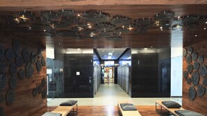 A modern hotel lobby with wooden floors, a central seating area with benches, and a ceiling with leaf-like decorations. - City View Oasis KS Bed Pool Hot Tub Gym (Mexico City)