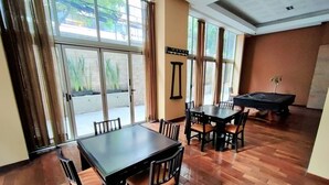 A dining area with a table and chairs, a pool table, and large windows with curtains. - The Polanco Signature Curated 2BR w Top Amenities (Mexico City)