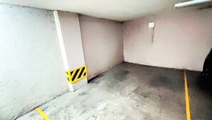 A parking garage with concrete floors and walls, marked parking spaces, and a caution sign on the wall. - The Polanco Signature Curated 2BR w Top Amenities (Mexico City)
