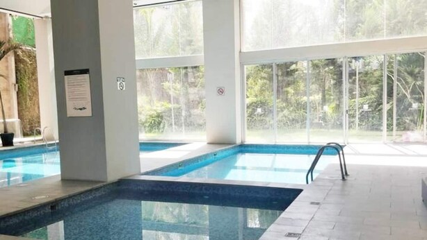 An indoor swimming pool with clear glass walls, a tiled floor, and a no-smoking sign. - The Polanco Signature Curated 2BR w Top Amenities (Mexico City)