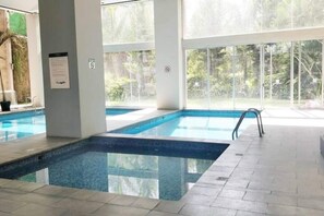 An indoor swimming pool with clear glass walls, a tiled floor, and a no-smoking sign. - The Polanco Signature Curated 2BR w Top Amenities (Mexico City)