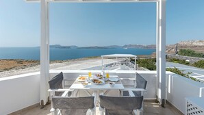 Une terrasse avec une table préparée pour le petit-déjeuner, offrant une vue sur la côte.