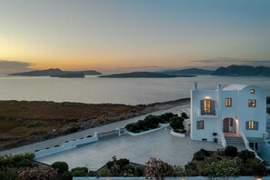A coastal property with a white building, a paved driveway, and a view of the sea and islands. - Hemera Holiday Home Villa on Santorini (Santorini)
