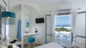 Une chambre avec un lit, un bureau, une chaise, une télévision et un balcon avec vue.