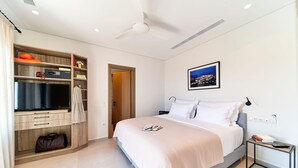 Una habitación de hotel moderna con cama, televisor, armario y mesita de noche.