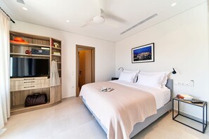 A modern hotel room with a bed, a TV, a wardrobe, and a bedside table. - Sigma Residences Sifnos (Sifnos)