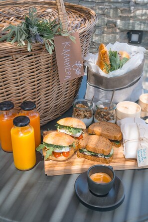 Une table avec des sandwichs, un panier de pain, des pots de condiments et une bougie.