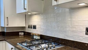A modern kitchen with white cabinets, a granite countertop, a gas stove, and a tiled backsplash. - 2 Bed Apartment - Sleeps 4, Balcony, Pets Ok (London)