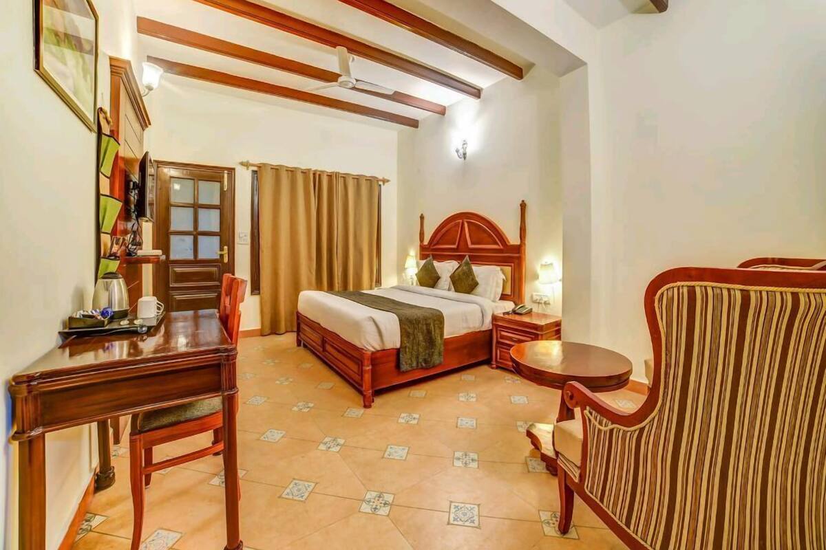 A hotel room with a bed, bedside table, chair, and a small round table.
