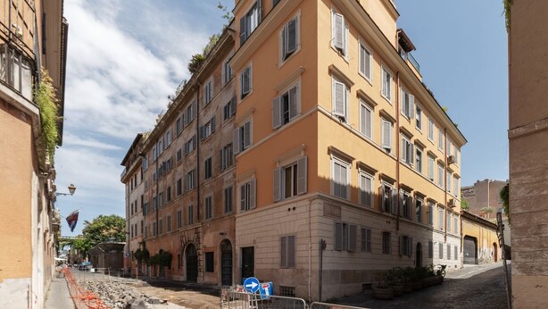 Un edificio de varios pisos con fachada amarilla, múltiples ventanas y una calle en su parte frontal.