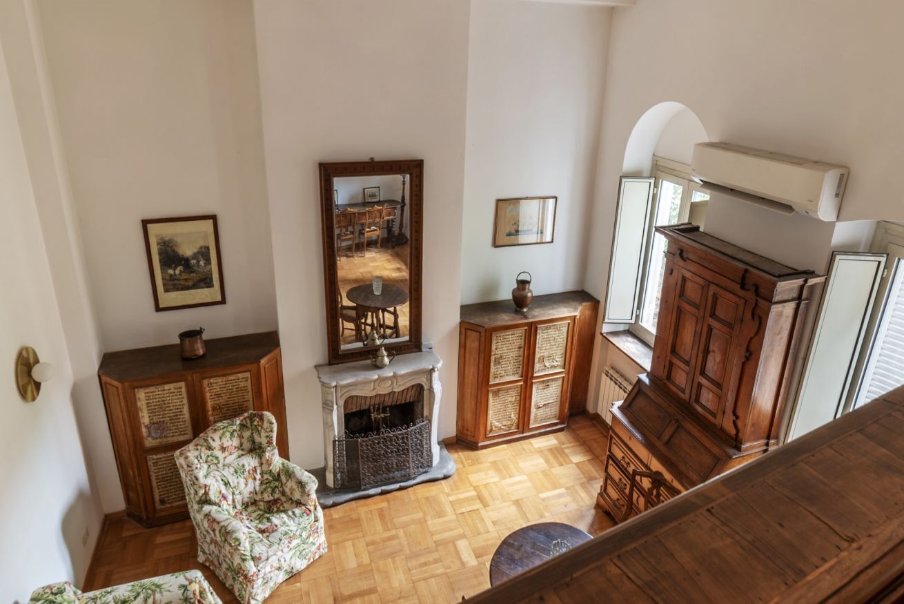 A room with a fireplace, wooden furniture, and a mirror reflecting a dining area.
