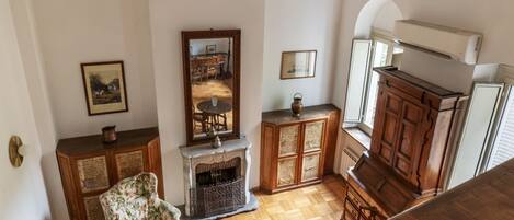 A room with a fireplace, wooden furniture, and a mirror reflecting a dining area.