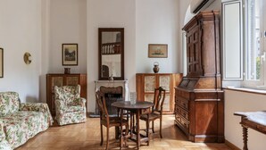Una habitación con suelo de madera, una mesa redonda con sillas, un sofá, una chimenea y un mueble de madera grande.