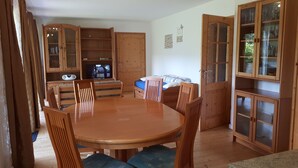 Un coin repas en bois avec une table ronde et des chaises, un téléviseur et des meubles de rangement en bois.