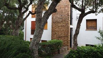 A pathway leading to a building with a brick chimney, surrounded by trees and greenery.