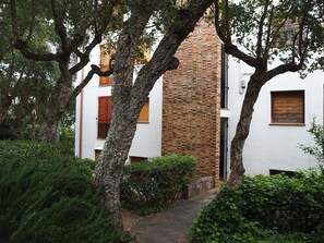 A pathway leading to a building with a brick chimney, surrounded by trees and greenery. - Apartament amb Espectaculars Vistes al Mediterrani (Palafrugell)