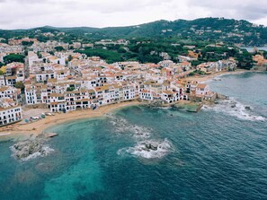 A coastal town with terraced buildings, a beach, and rocky outcrops in the water. - Apartament amb Espectaculars Vistes al Mediterrani (Palafrugell)